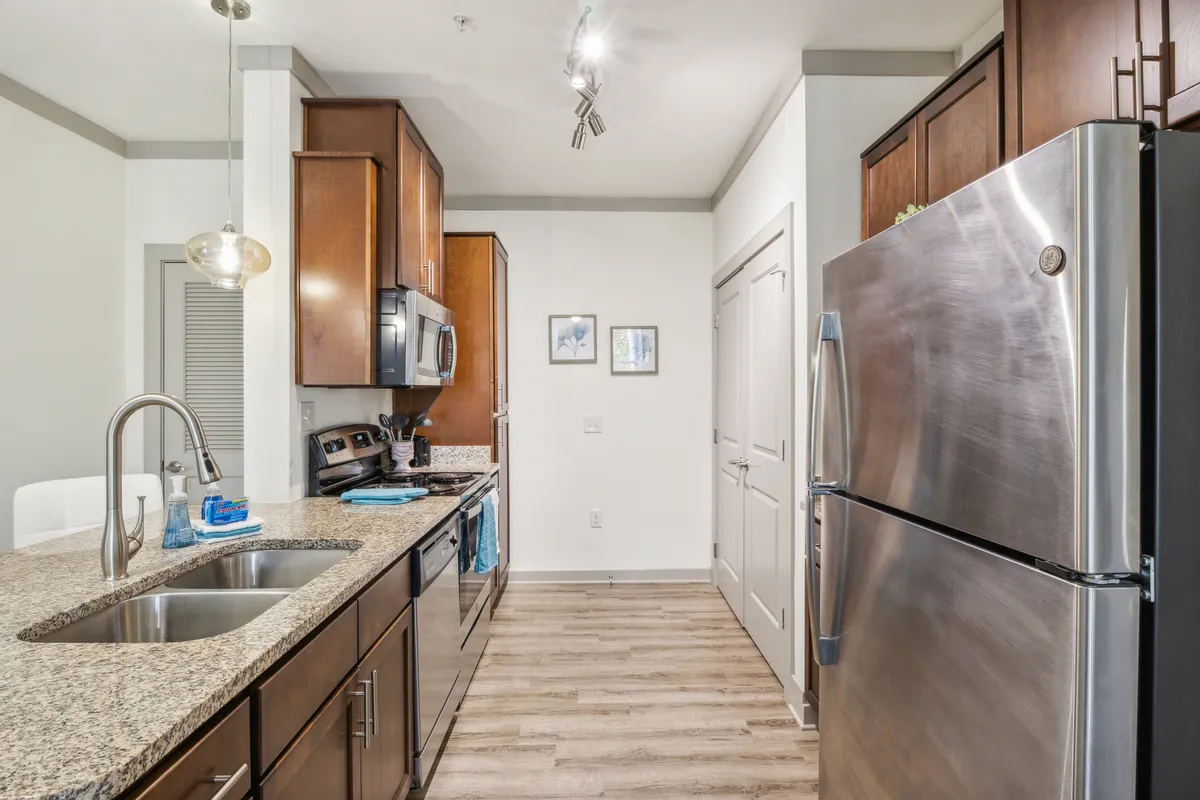 A modern kitchen with a large granite island at the center, stainless steel appliances, elegant light fixtures, and an open layout perfect for cooking and entertaining. The space feels bright, welcoming, and ready for group gatherings or family meals.