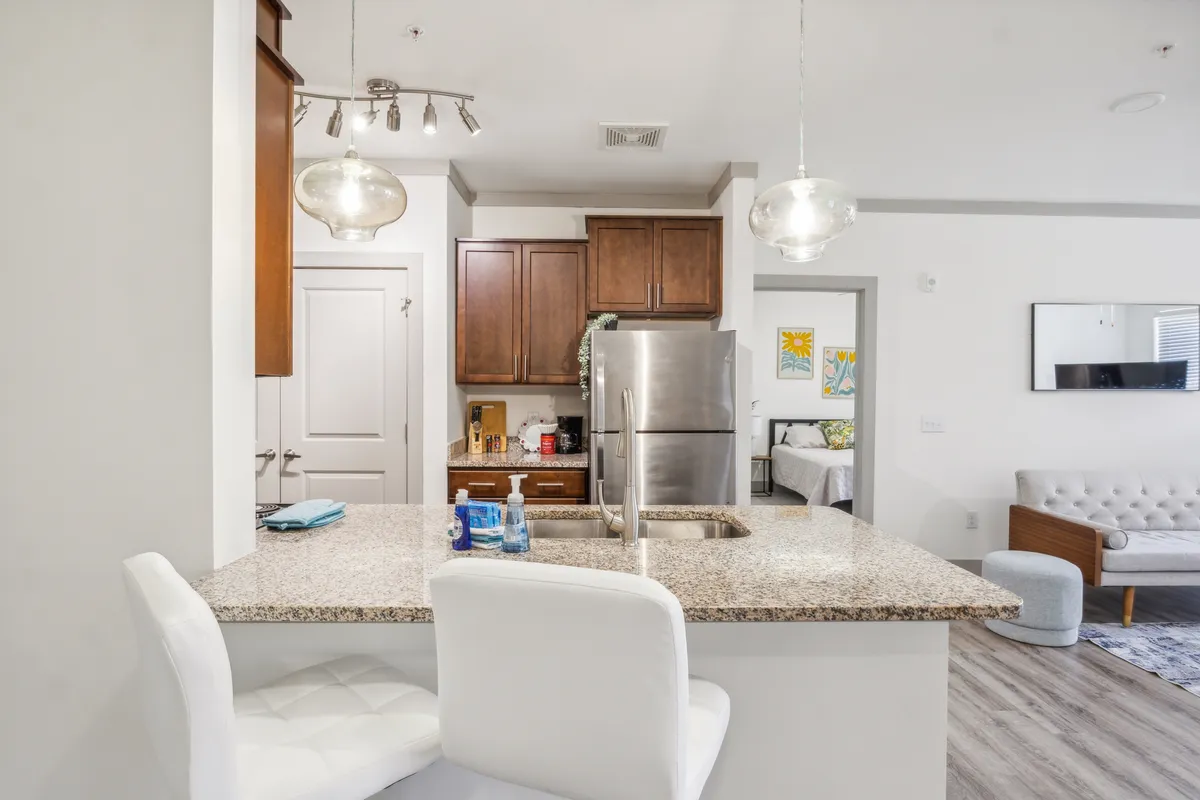 A beautifully appointed kitchen featuring a granite countertop, stainless steel appliances, inviting bar stools at a breakfast bar, and warm wooden cabinetry. The scene captures a spacious, modern culinary space that is both functional and stylish.